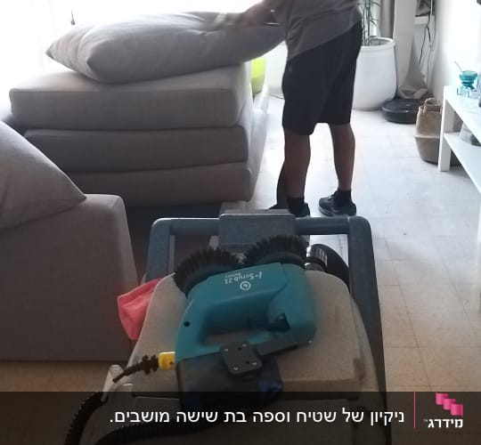 אדם מנקה ספה עם מכונת ניקוי חשמלית